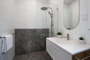 La salle de bains blanche est pourvue d'un lavabo et d'une douche. dans l'établissement Wynvale Cottage Hepburn, à Hepburn