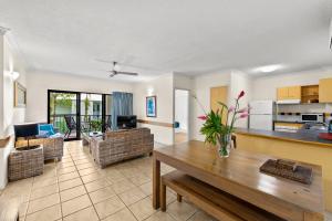 a living room with a table and a kitchen at Nautilus Holiday Apartments in Port Douglas