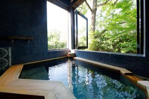 a swimming pool in a room with a window at Ryokan Konomama in Minami Aso