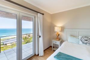 a bedroom with a bed and a view of the ocean at Comfy Holiday Home - No Loadshedding - By Peak Management in Wilderness