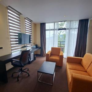 a living room with a couch and a desk with a television at Viceroy Luxury Mountain Resort in Munnar