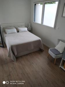1 dormitorio con cama, ventana y silla en La Rochelle- Puilboreau Studio tout confort, en Puilboreau