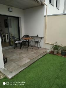 un patio con mesa, sillas y césped en La Rochelle- Puilboreau Studio tout confort, en Puilboreau