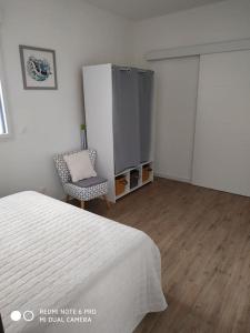 1 dormitorio con cama, silla y armario en La Rochelle- Puilboreau Studio tout confort, en Puilboreau