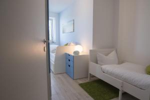 クックスハーフェンにあるStrandhaus-Nordseebrandung-Fewo-B3-4の白い小さなベッドルーム(ベッド1台、テーブル付)