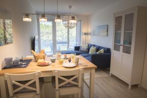 eine Küche und ein Wohnzimmer mit einem Tisch und einem blauen Sofa in der Unterkunft Strandhaus Nordseebrandung Fewo B3.4 in Cuxhaven