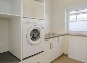 a white laundry room with a washing machine at Ferienhaus Seeblick in Walchum