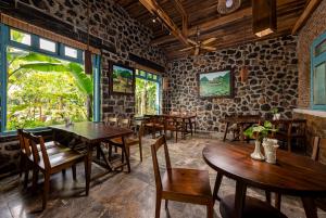 a restaurant with wooden tables and chairs and a window at ChezCao Rice Field Ecolodge Ninh Binh in Ninh Binh