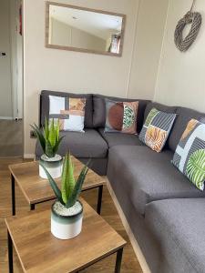 a living room with a couch and two tables with plants at Hughes Holiday Home in St Osyths in Jaywick Sands