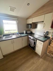 a small kitchen with a sink and a stove at Hughes Holiday Home in St Osyths in Jaywick Sands