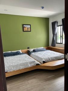 two beds in a bedroom with green walls at Tom Homestay Quy Nhơn in Quy Nhon