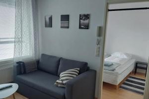 ein Wohnzimmer mit einem blauen Sofa und einem Bett in der Unterkunft Kotimaailma Apartments Sammonkatu 6 in Jyväskylä