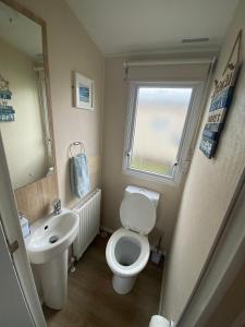 a small bathroom with a toilet and a sink at Hughes Holiday Home in St Osyths in Jaywick Sands