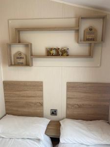 2 camas en una habitación con estanterías encima en Hughes Holiday Home in St Osyths, en Jaywick Sands