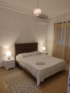 a bedroom with a bed with two night stands and two lamps at Nice stay jardins de Carthage in Al Karm