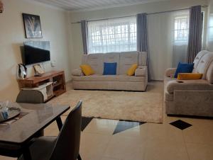 un soggiorno con divano e tavolo di Exquisite 2BR Ensuite Apartment close to Rupa Mall, Mediheal Hospital, and St Lukes Hospital a Eldoret