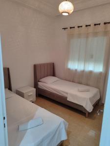 a bedroom with two beds and a chandelier at Nice stay jardins de Carthage in Al Karm