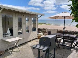 a beach house with a grill and a table and an umbrella at Beachhaven116 Lovely beachside house Lower Largo in Lower Largo