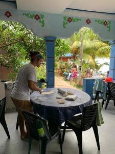 Ein Mann steht an einem Tisch mit einem blauen Tischtuch. in der Unterkunft Ella's Place Salang Tioman in Tioman Island