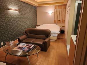 um quarto de hotel com um sofá e uma cama em スタイリッシュ武里 em Koshigaya