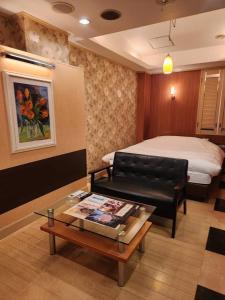 ein Hotelzimmer mit einem Bett und einem Couchtisch in der Unterkunft スタイリッシュ武里 in Koshigaya