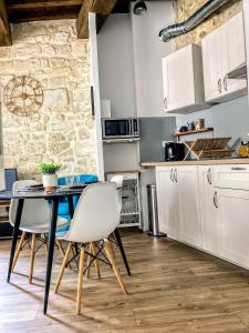 - une cuisine avec des placards blancs, une table et des chaises dans l'établissement Logement 3 Apparts Centre historique St Gilles MaisoncarreeConciergerie, à Saint-Gilles