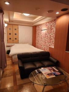 ein Wohnzimmer mit einem Sofa und einem Glastisch in der Unterkunft スタイリッシュ武里 in Koshigaya