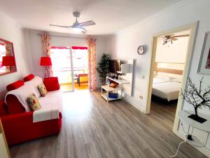 ein Wohnzimmer mit einer roten Couch und einem Bett in der Unterkunft Apartment in Puerto de Santiago. Jardines del Mar in Puerto de Santiago + 13 Fotos