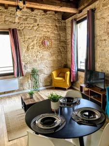 ein Wohnzimmer mit einem Tisch und einer Steinmauer in der Unterkunft Immeuble 3 Apparts Centre historique St Gilles MaisoncarreeConciergerie in Saint-Gilles
