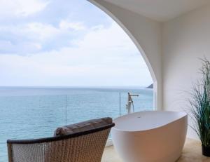 Elite Atoll Khanom - Luxury Coastal Escape في خانوم: حمام مع حوض استحمام وإطلالة على المحيط