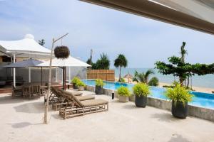 a patio with chairs and umbrellas next to a pool at Elite Atoll Beachfront Hotel in Khanom