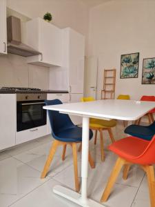 a kitchen with a white table and colorful chairs at ELISIR' S APARTMENT in Caserta
