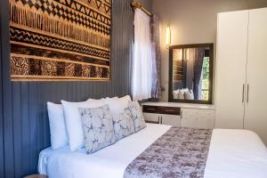 1 dormitorio con 1 cama con sábanas y almohadas blancas en Pangolin Nest Boutique Hotel, en Kampala