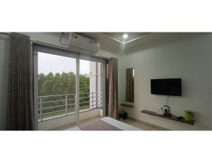 a bedroom with a large window with a view of a balcony at Hotel Hill View, Vadatalav, Gujarat in Hālol