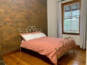 a bed in a room with a brick wall at Quarryman Cottage @ 102 in Bowral