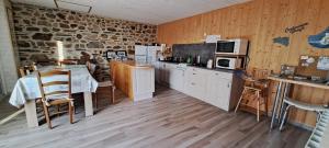 uma cozinha com uma mesa e uma parede de pedra em Couloumine breizh em Saint-Aignan