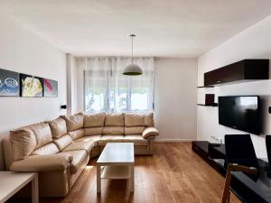 een woonkamer met een bank en een tv bij Luminoso Apartamento a 10 minutos de Granada con Piscina in Alhendín