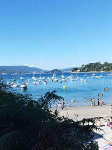 a group of people on a beach with boats in the water at Apartamento Illa de Tambo in Marín