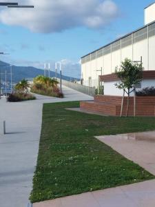 a building with a sidewalk next to a field of grass at Apartamento Illa de Tambo in Marín