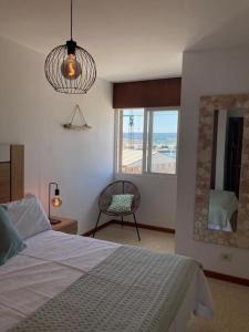 ein Schlafzimmer mit einem Bett, einem Spiegel und einem Stuhl in der Unterkunft Apartamento Illa de Tambo in Marín