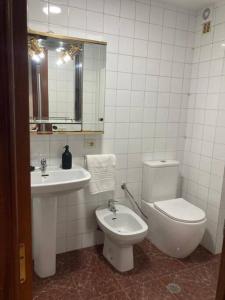 a white bathroom with a toilet and a sink at Apartamento Illa de Tambo in Marín