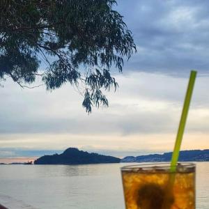 a drink with a straw sitting on a table near the water at Apartamento Illa de Tambo in Marín