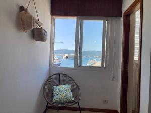 a chair with a pillow sitting in front of a window at Apartamento Illa de Tambo in Marín