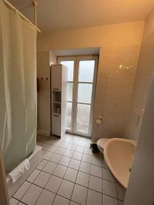 a bathroom with a tub and a sink and a refrigerator at Alter Wirt Thalkirchen in Munich