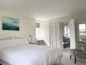a white bedroom with a bed and a chair at The Mount Somerton Apartments - Somerset Private, Peaceful & 400 mtres from the village in Somerton