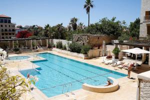 a large swimming pool with people sitting around it at Deluxe 2BR Apt w Pool in Historical Jaffa by Sea N' Rent in Tel Aviv