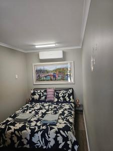 um pequeno quarto com uma cama e um quadro na parede em Almost Off Grid Tranquillity em Katherine