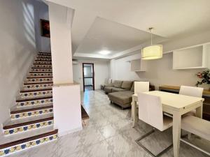 ein Wohnzimmer mit einer Treppe, einem Tisch und einem Sofa in der Unterkunft Casa adosada junto a la playa de El Perelló in Sueca