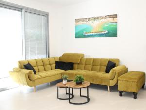 a living room with a yellow couch and a table at Private Jacuzzi, Beach View, Gym, Low Fee For Off-Site Indoor Pool, Spa & Kosher Breakfast ג'קוזי פרטי אם נוף ים, אפשרות לארוחת בוקר כשר, בריכה מקורה, וספא בתשלום ממש מוזל in Ashkelon