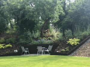 un jardín con sillas y flores y una valla en Country house, en Killyhevlin